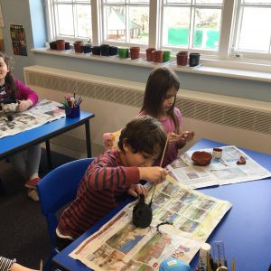 children painting pottery at school