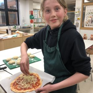 school girl making pizza