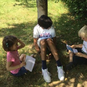 three children reading outdoors
