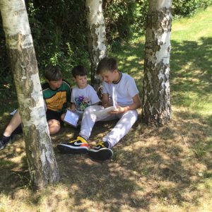Boys sat by trees reading