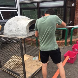 student making pizza oven