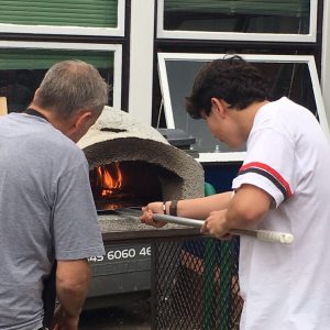 student lighting a pizza oven