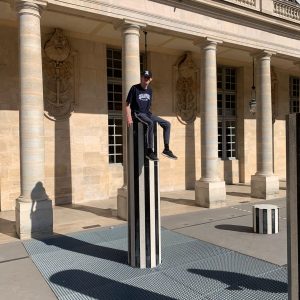 Student stood on a very tall black and white striped pillar