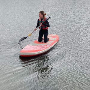 Student pushing paddleboard with oar