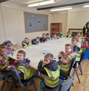 children in hi vis jackets at a table